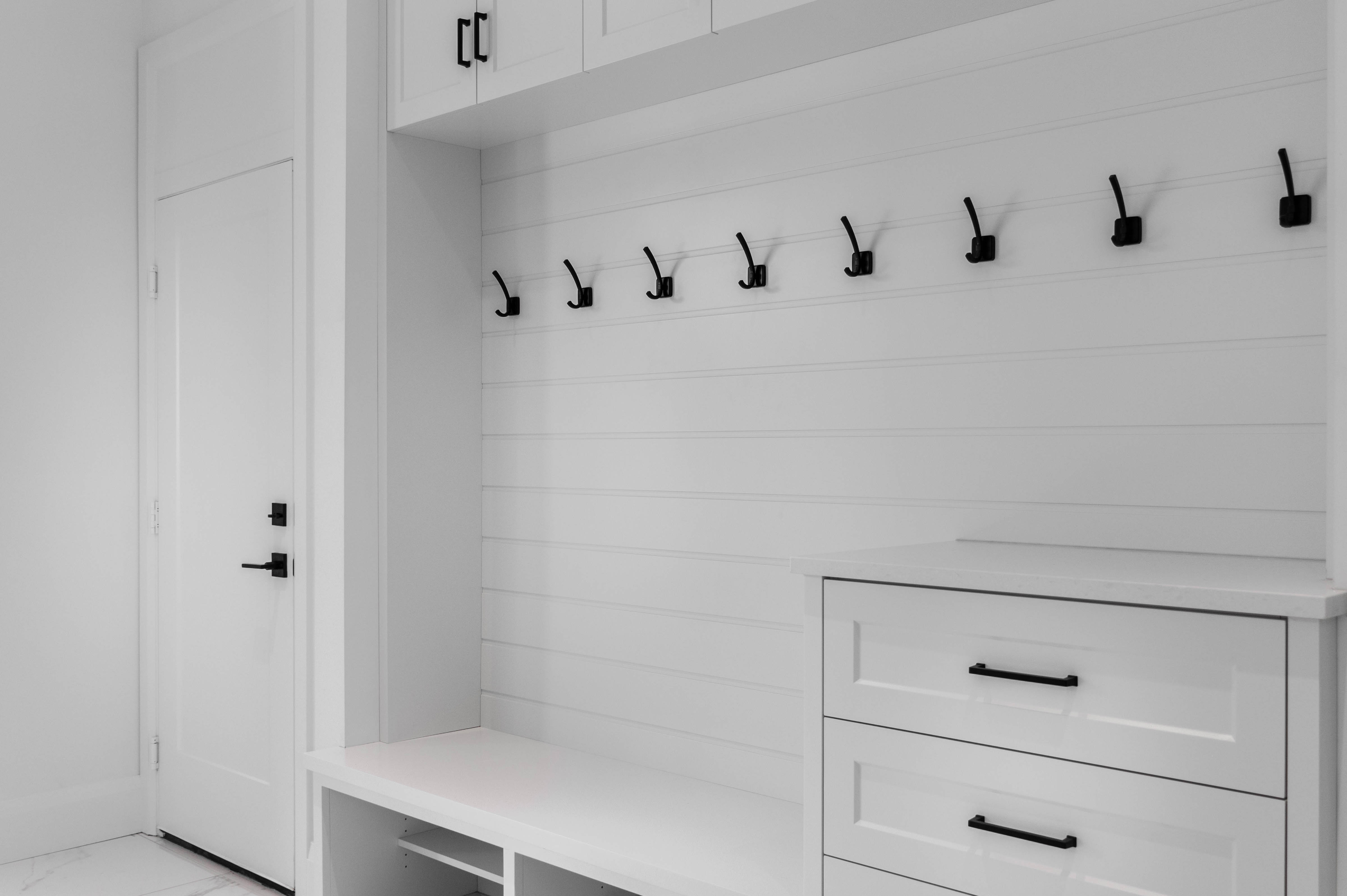 white painted cabinetry in mudroom with black accents, bench seating, drawers and doors for storage. 