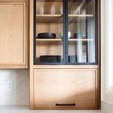 Close up of corner oak wood kitchen cabinets featuring glass panel storage