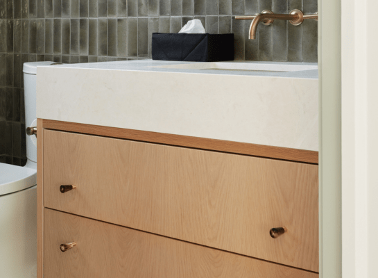 single sink white oak bathroom vanity with green tiles and brass hardware