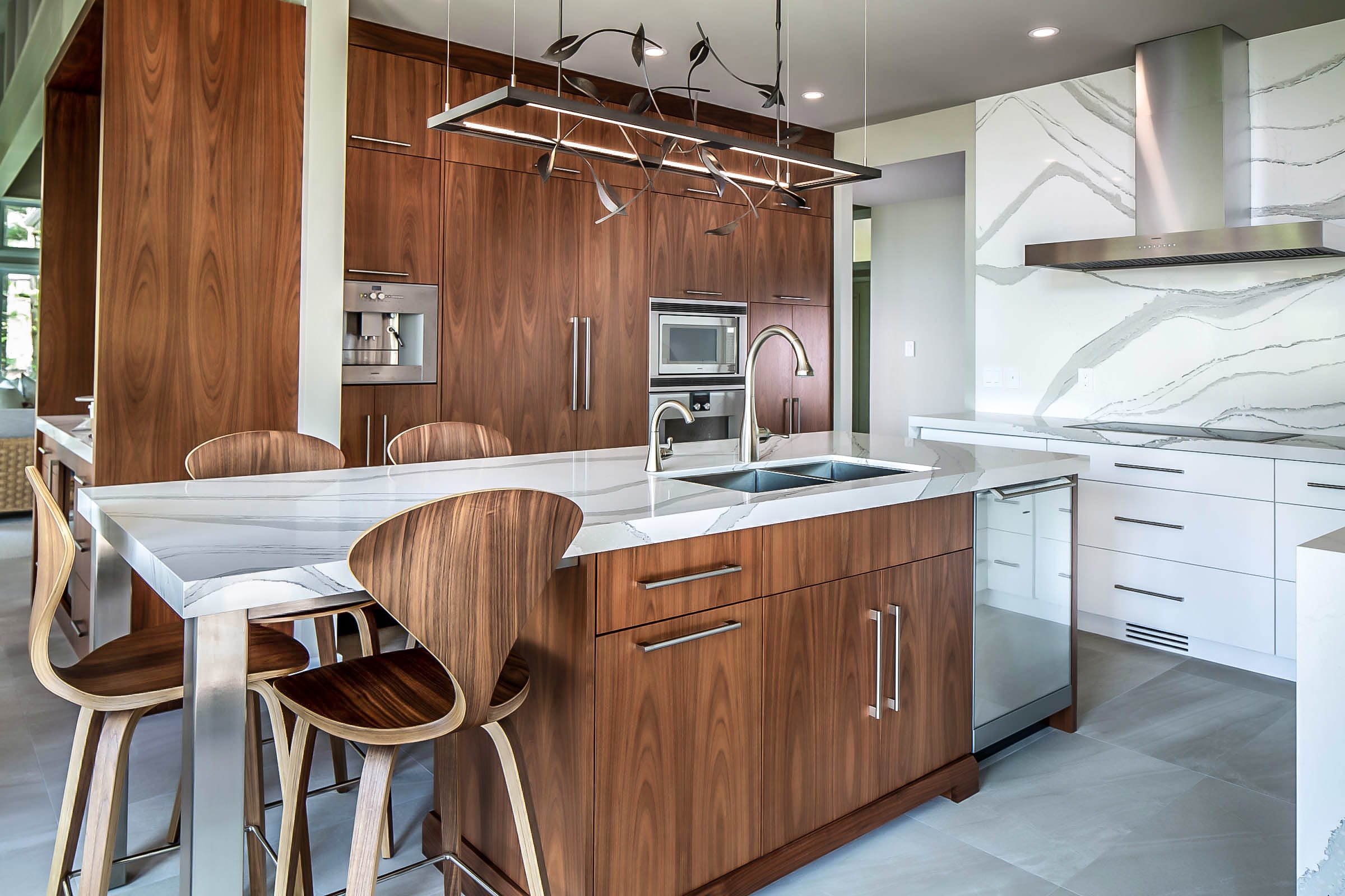A white and walnut modern custom kitchen with a full height quartz backsplash.