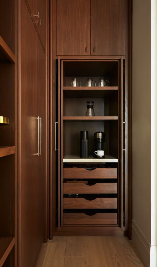 Open doors of a pantry from walnut wood showcasing pocket doors 