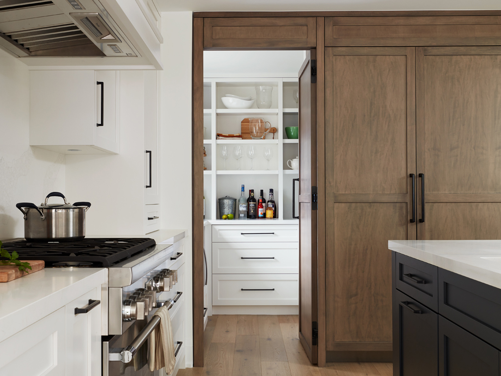 Modern pantry with walnut doors and white kitchen cupboards