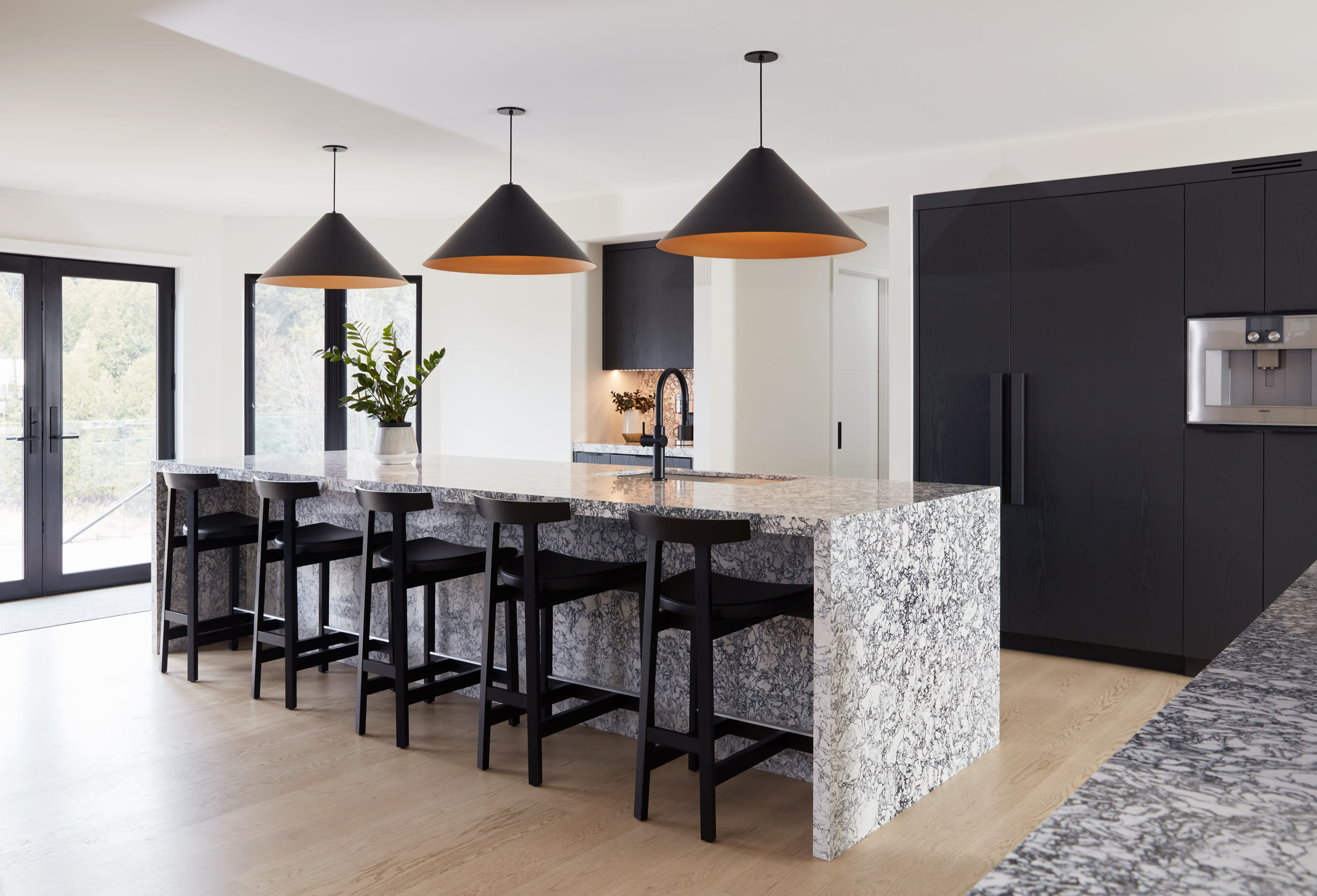 Overview from of kitchen space with waterfall island and painted black cabinets