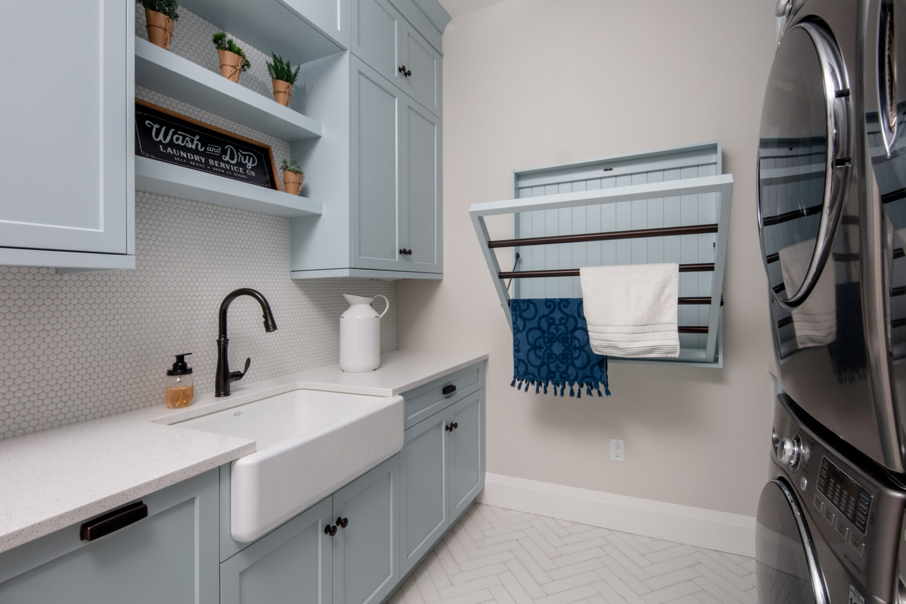 Laundry room with baby blue custom cabinets and a matching wall-mounted drying rack