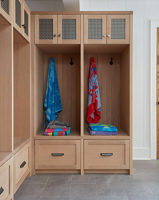 Rift white oak cabinetry in mudroom with open shelves, hooks to hang towels, drawers and doors. 