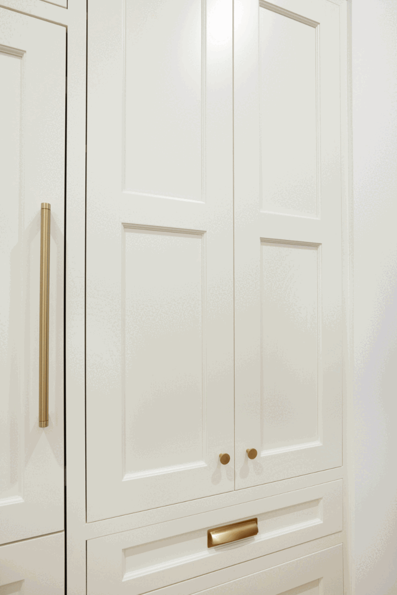 White pantry cabinet with bronze hardware with adjustable shelves and roll-out drawers