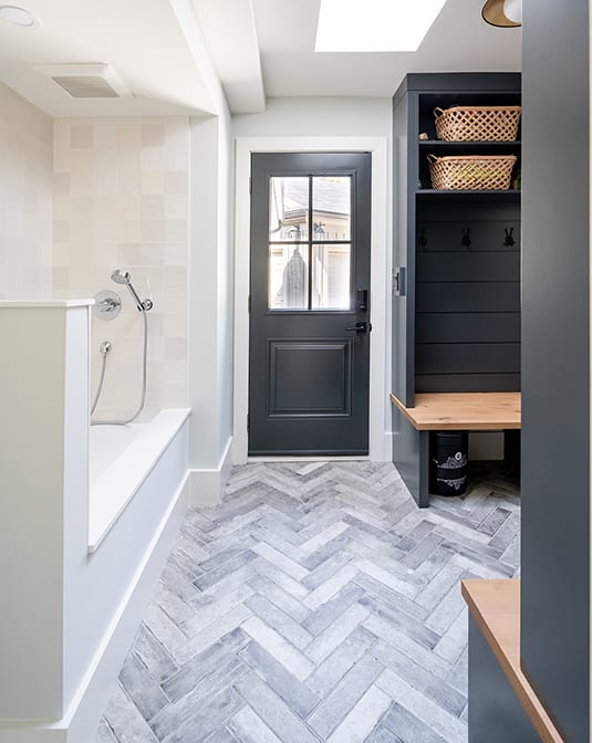 black and wood stained cabinetry in mudroom with custom dog shower