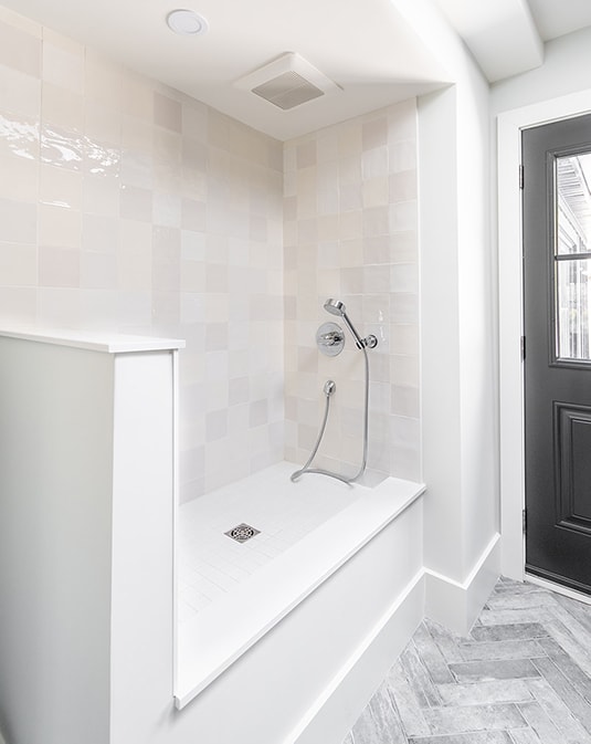 dog washing station with white cabinetry in mudroom