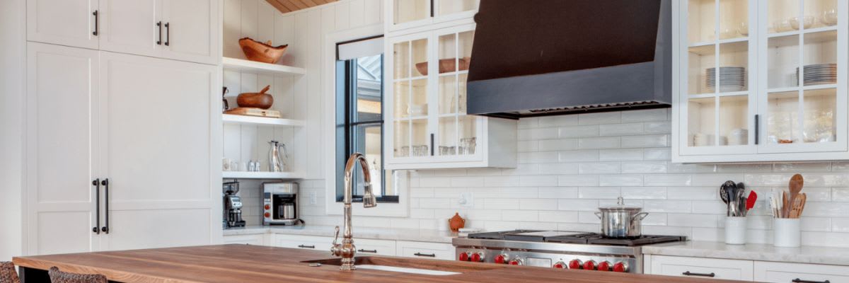 White kitchen with wood island and open shelving in the corner