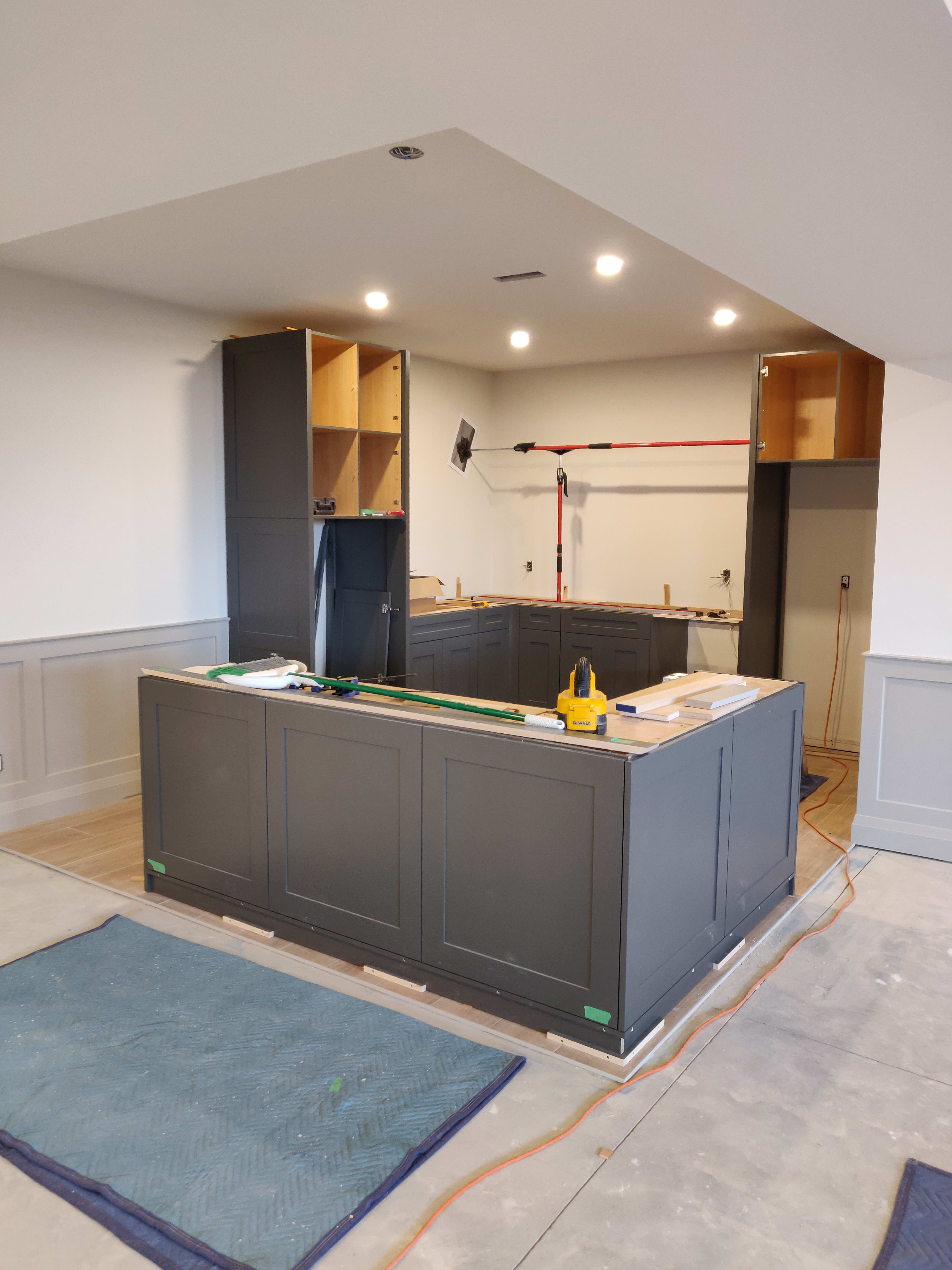 Step 1 of a kitchen install process. Lower cabinets are in place with upper cabinet doors not placed yet.