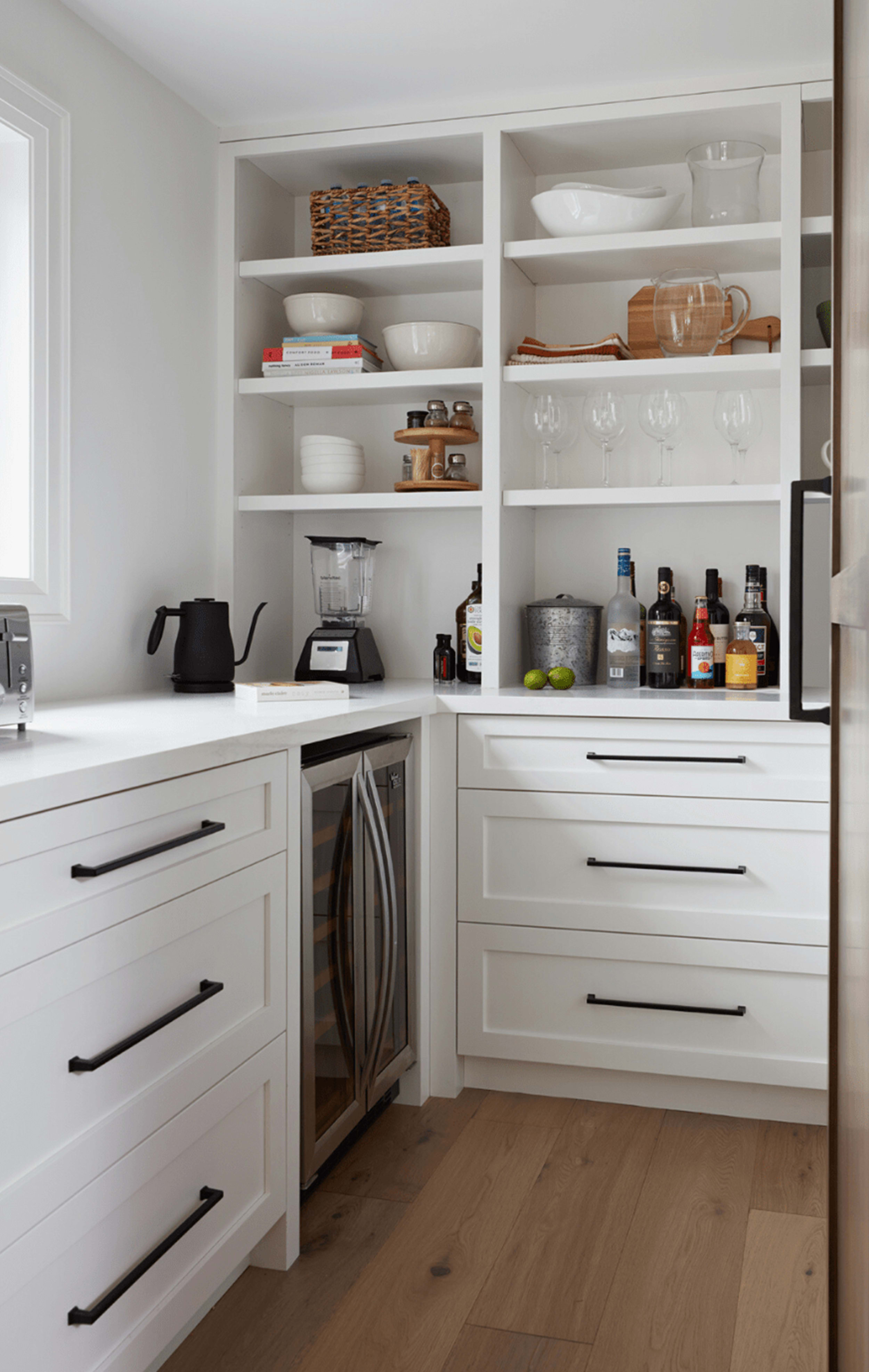 Bright butler's pantry with white cabinetry and open shelving up top with serving dishes and appliances displayed