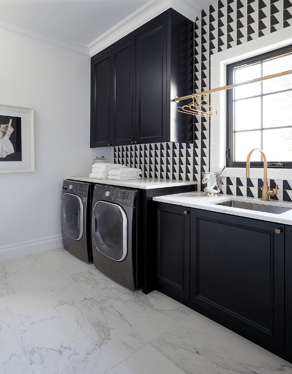 Luxury laundry room with black custom cabinetry, gold accents, and white quartz countertops 