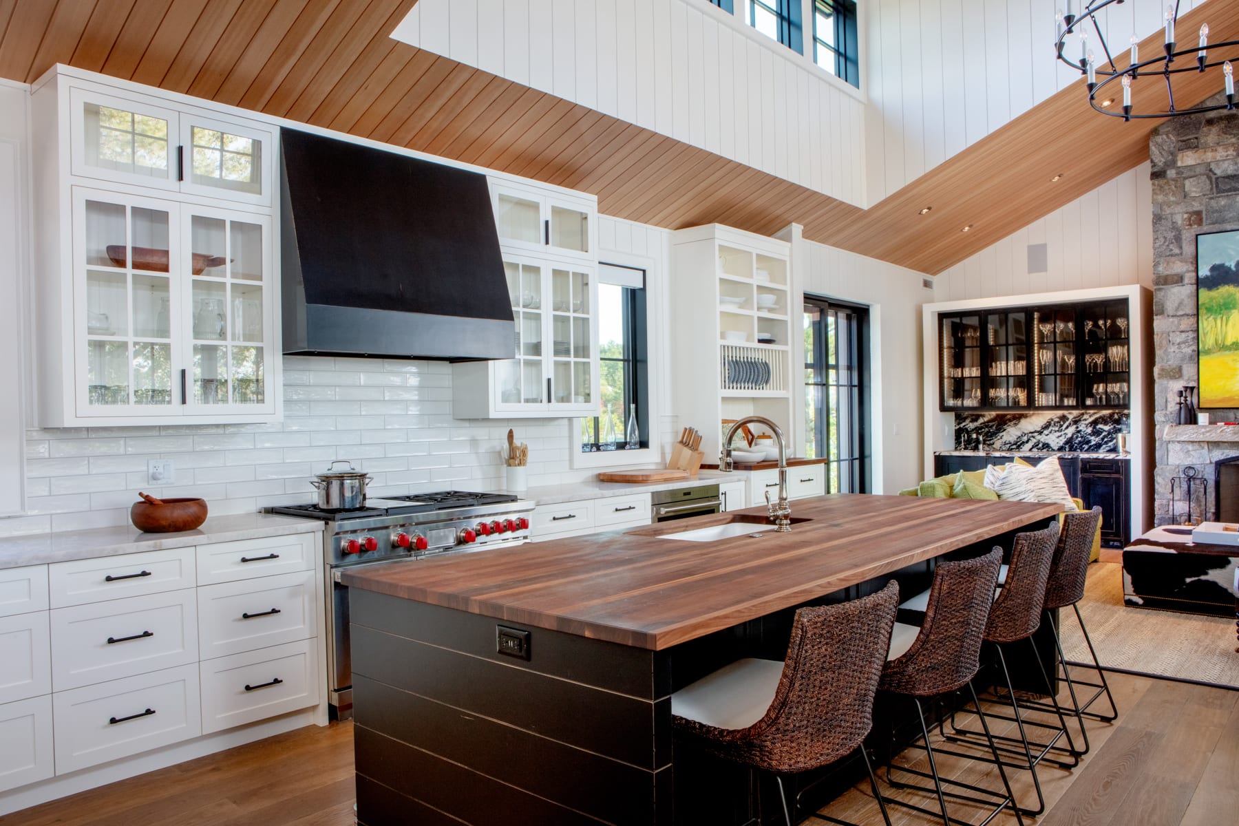A transitional custom cottage kitchen with painted white cabinets and a distressed black island and range hood.
