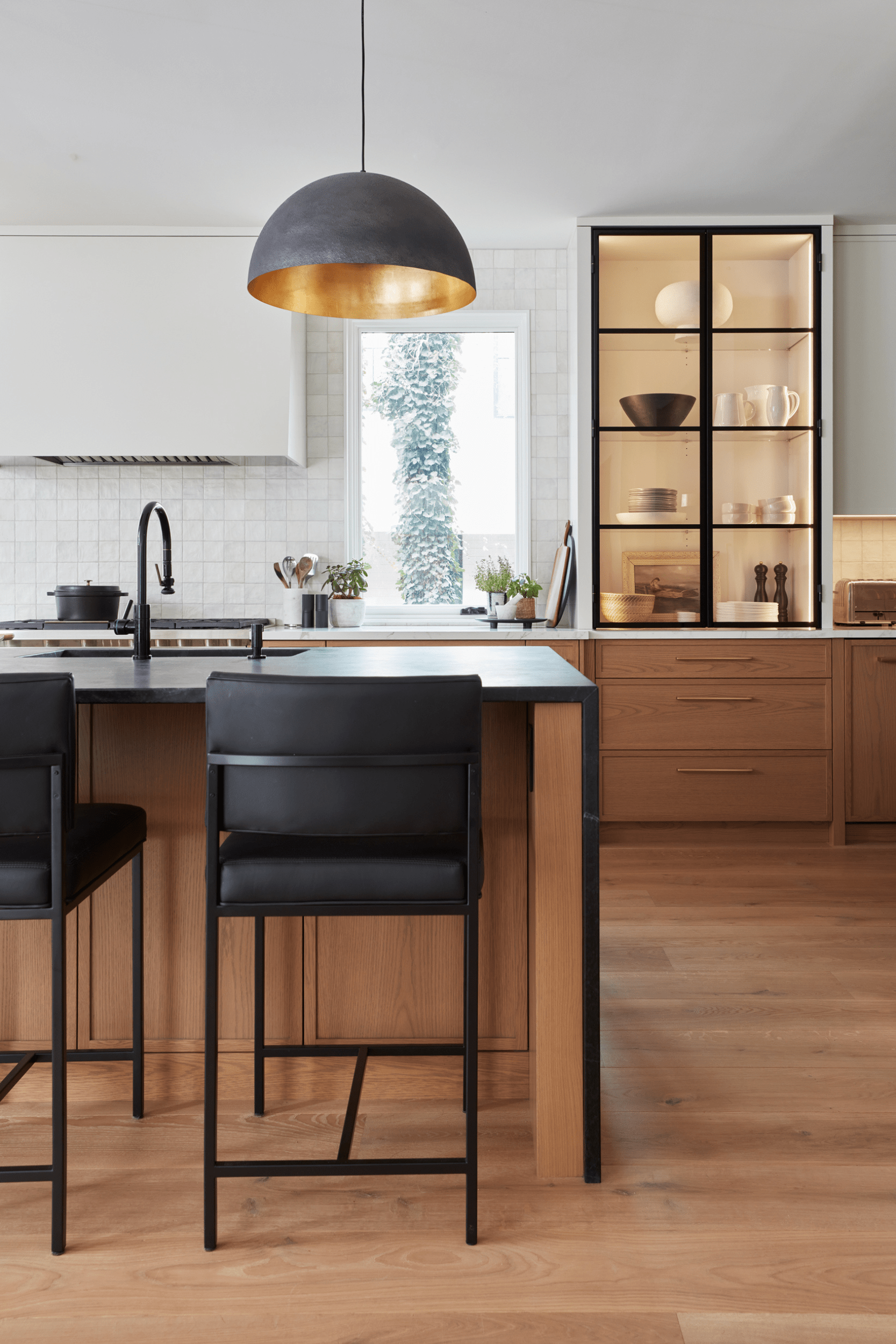 A transitional white oak kitchen with black metal countertop top hutches