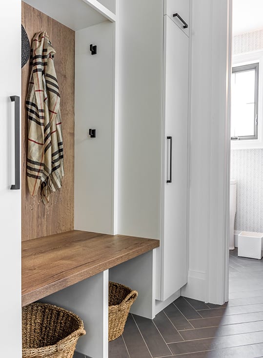 Brown wood stained cabinetry surrounded by white painted cabinetry in mudroom