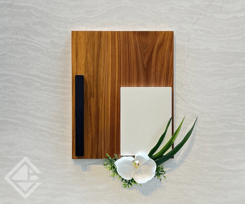 Flat cut walnut cabinet door with black hardware on a light quartz background with natural floral decor