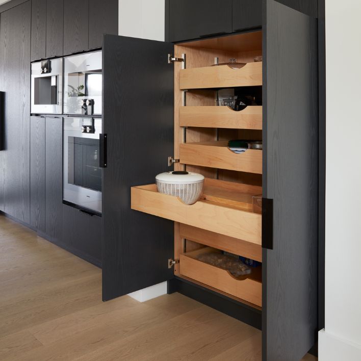 Dark wood kitchen pantry cabinet open with sliding tier shelf organzier built in for kitchen storage.