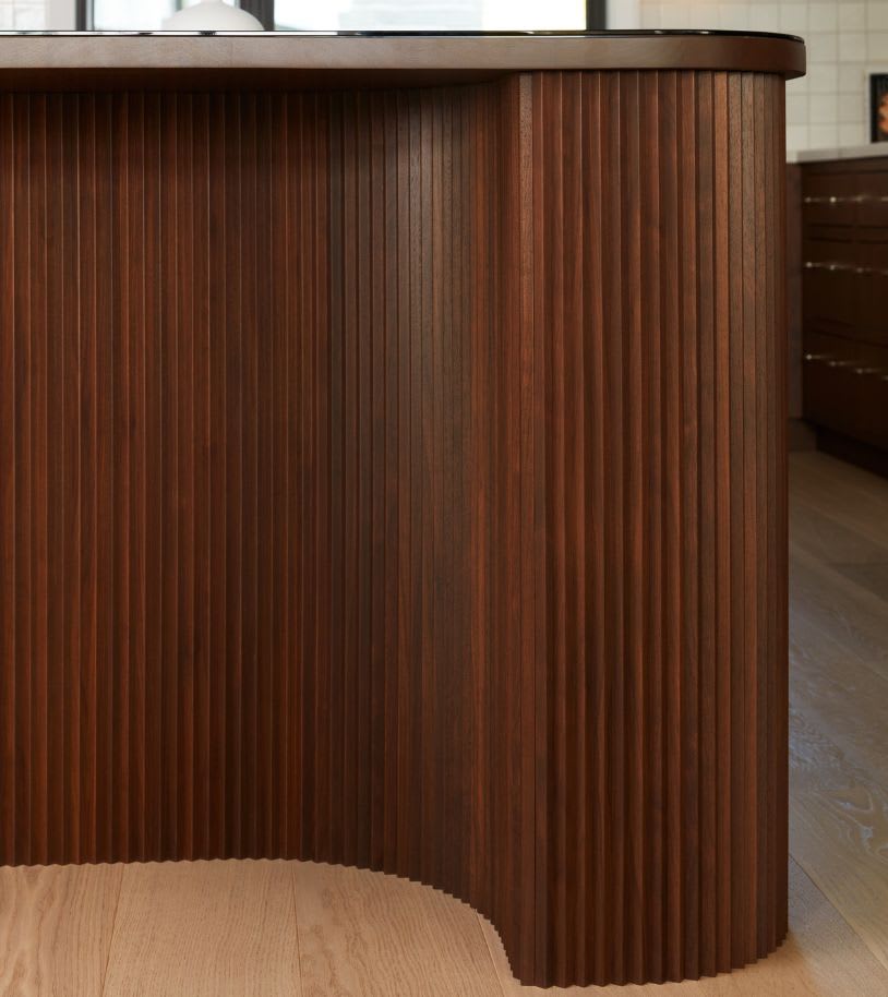 Close up of walnut custom made kitchen island with individual cut pieces to form a curved island