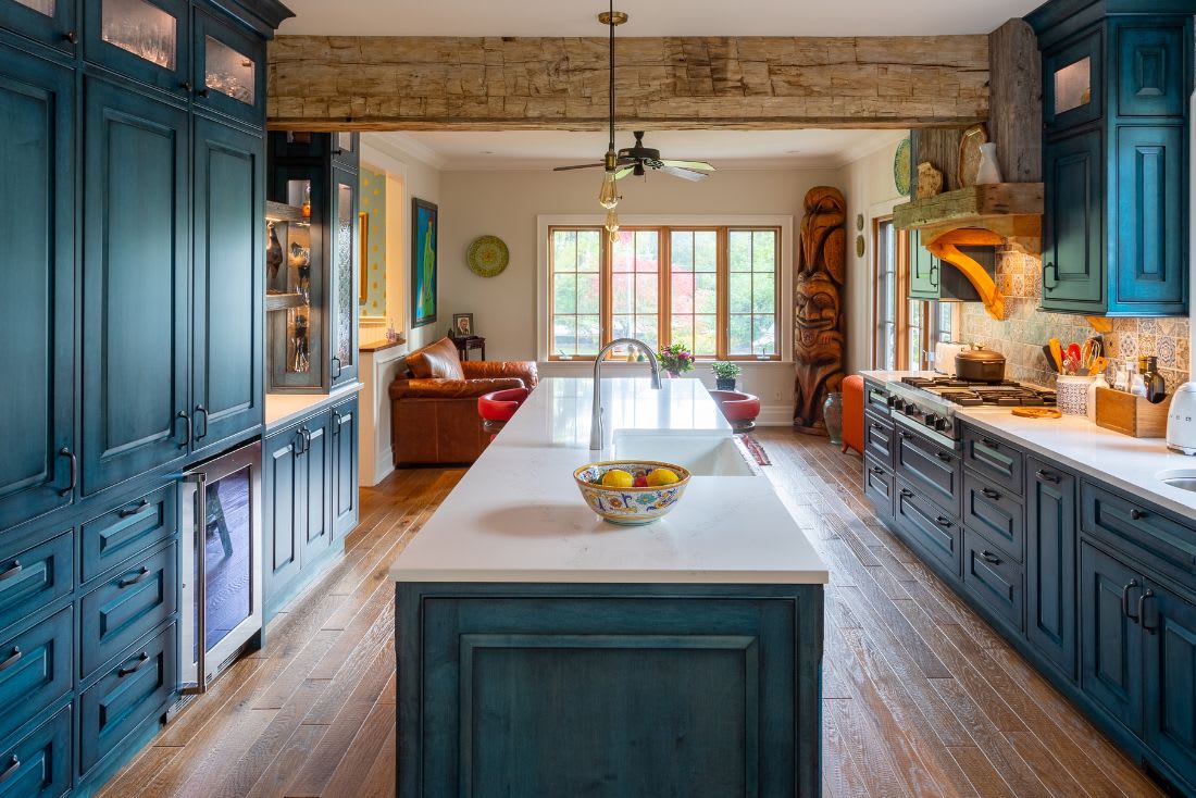 Galley kitchen layout featuring blue custom wood cabinets with island in the centre