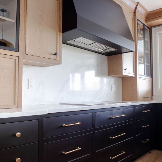 Dark kitchen cabinets with accents of light wood and custom range hood