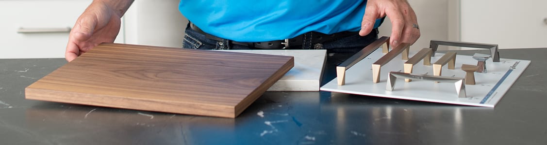 Close up of the hands of a Chervin Kitchen & Bath designer showing samples of wood and hardware