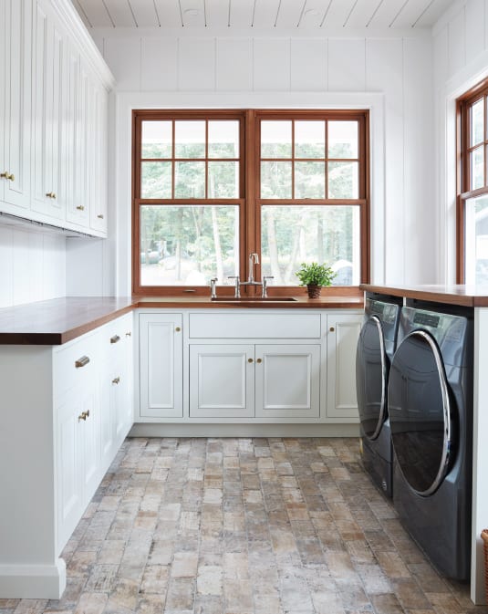 muskoka cottage luxury laundry room with white cabinets and wood countertops