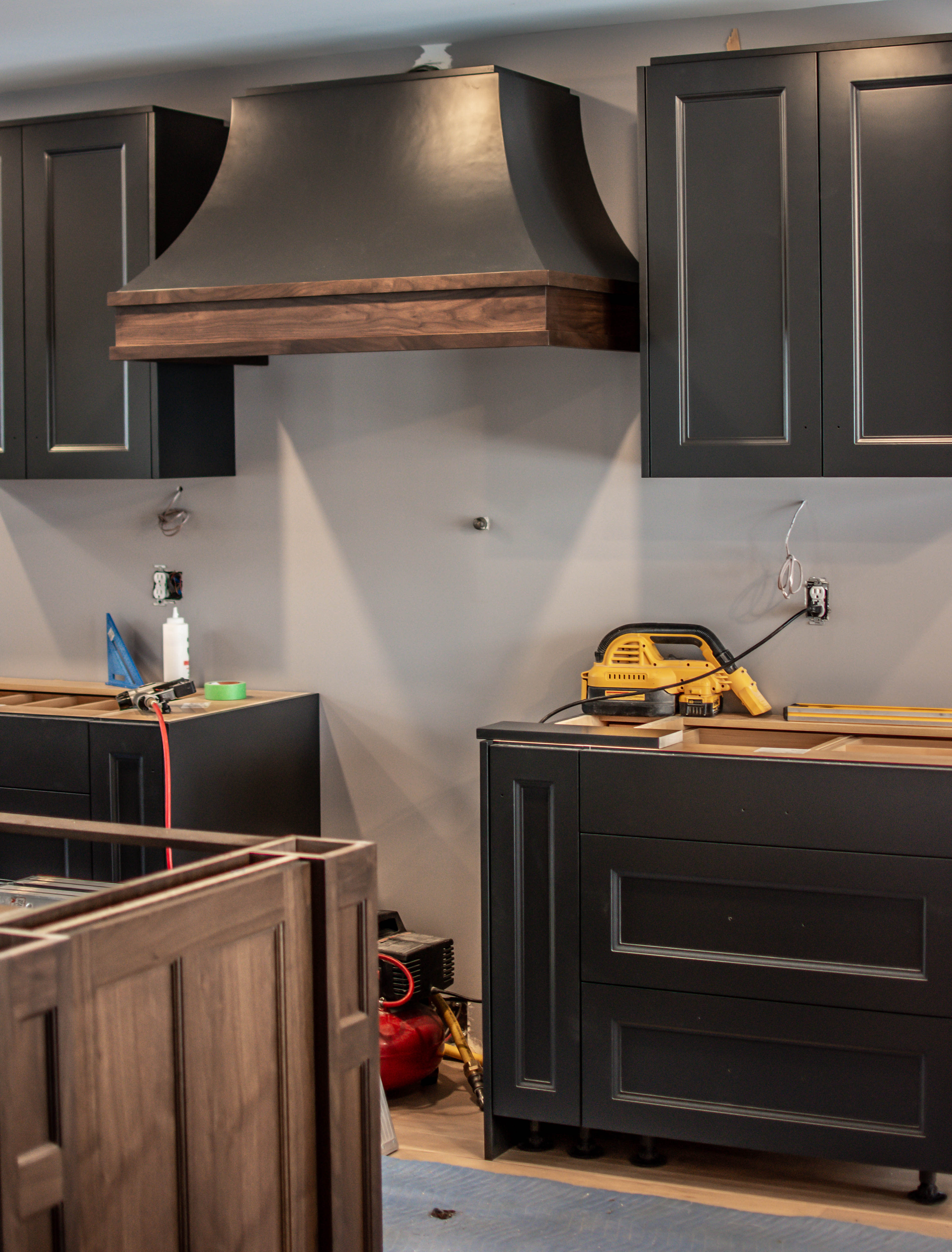 Step 2 of a kitchen install process. Lower and upper cabinets are in place with no countertop installed yet.